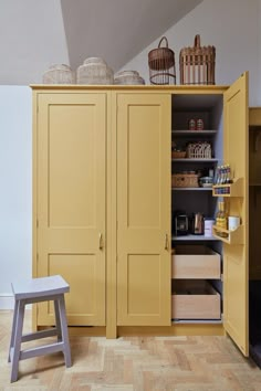 an open yellow cabinet with baskets and other items on the top shelf next to it