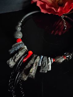 I made this necklace in a modern style with an ethnic touch. To create this necklace I used different types of stones and crystals. The necklace is made of large irregular flakes of agate and bone stone galvanized in black and silver, colored quartz, coral slats, lava stone and glass and resin beads. The central part of the necklace is made with rather large stones which make it very eye-catching. The main color is black with a touch of red given by the coral sprigs. This necklace is the fruit of my imagination, it is an artistic jewel created with various natural stones and crystals. The necklace is rigid but rests naturally on the neck, very comfortable to wear. The back is made with silicone cord. The necklace is very bright, 48cm long with an adjustable lobster clasp. It is a particula Bohemian Necklace With Freeform Natural Stones, Bold Red Handmade Necklace, Red Multi-strand Necklaces With Natural Stones, Luxury Multi-strand Statement Necklaces, Luxury Multi-strand Statement Beaded Necklace, Color Quartz, Designer Necklace, Gemstone Art, Necklace Elegant