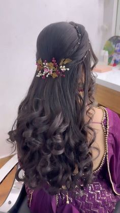 the back of a woman's head with long hair and flowers in her hair