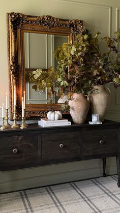 a table with two vases and a mirror on it