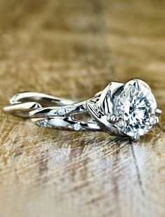 a close up of a ring on top of a wooden table with a diamond in the center