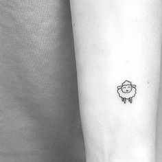 a small sheep tattoo on the left inner forearm and wristband is shown in this black and white photo