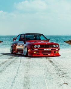 a red car parked in front of the ocean