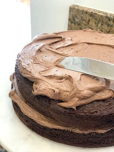 a cake with chocolate frosting and a knife on it's side, ready to be cut