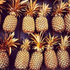 several pineapples lined up against a wooden wall