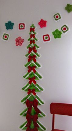 a christmas tree made out of paper on the wall next to a chair and other decorations