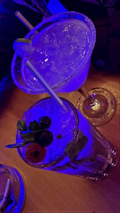 two glasses with strawberries in them sitting on a table