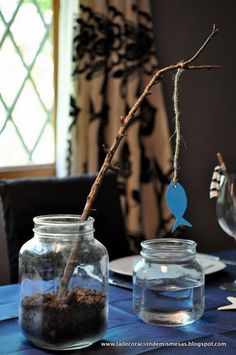 the table is set with two glass jars and one has a branch sticking out of it