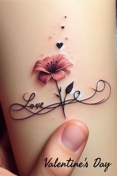 a person holding up a tattoo with a flower on it's arm and the word love written in cursive writing