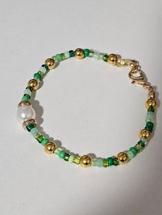 Add a touch of elegance to your collection with the "Emerald Dewdrop" bracelet, a beautifully crafted piece that blends simplicity with sophistication. This bracelet features vibrant green seed beads, reminiscent of fresh morning dew on lush leaves, and is gracefully accented with a lustrous pearl that adds a timeless charm. The secure clasp ensures a perfect fit, making it both stylish and practical for everyday wear. Whether you're dressing up for a special occasion or adding a subtle pop of color to your ensemble, the "Emerald Dewdrop" bracelet is a versatile and enchanting accessory. Adjustable Green Bracelets With Gold Beads, Adjustable Green Beaded Bracelets With Gold Beads, Dainty Green Beaded Bracelets, Green Beaded Bracelet As Gift, Dainty Green Beaded Bracelets With Colorful Beads, Green Beaded Bracelet With Gold Beads, Green Pearl Bracelet With Colorful Beads, Green Polished Beads Bracelet, Green Beaded Bracelet With Tiny Beads As Gift