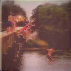 people jumping into the water from a bridge