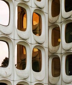 an unusual building with many windows on the side and trees in the window sill