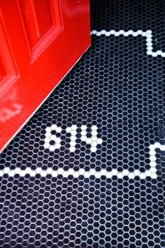 a red door with the number four painted on it next to a black and white mat