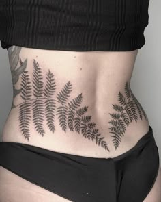 a woman's lower back tattoo with fern leaves on her stomach and bottom part