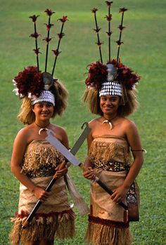 two young women dressed in native american garb holding knives and wearing headdress