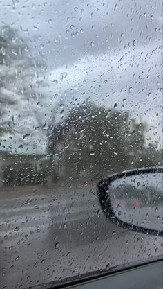 rain drops on the windshield of a car as it drives down a road in the rain