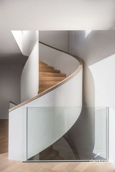 a spiral staircase with glass railing and wooden handrail