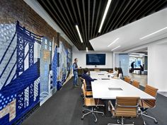 people are sitting around a conference table in an office with blue and white tiles on the wall