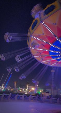 an amusement park at night with lights on the carousels and rides in motion behind them