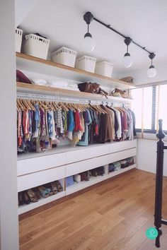 a closet with lots of clothes and shoes hanging on the wall next to a window