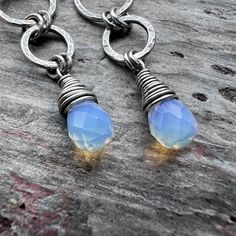 These long dangle earrings are handmade from sterling silver and Opalite. The small Opalite teardrops are wrapped in sterling silver. Above the teardops are a set of rings which I have formed, soldered, and hammered by hand. The earrings dangle from handmade sterling silver earwires. The silver has been oxidized and polished to create an antique patina finish.Be sure to see all photos and video for size and color reference.Opalite: About 5x7mmTotal Earring Length: Just over 2 inchesTotal Earring Nickel Free Briolette Teardrop Earrings In Sterling Silver, Nickel-free Briolette Teardrop Sterling Silver Earrings, Unique Teardrop Sterling Silver Earrings, Handmade Sterling Silver Long Drop Teardrop Earrings, Handmade Sterling Silver Teardrop Pendant Earrings, Silver Teardrop Jewelry With Hand-wrapped Detail, Unique Hand Wrapped Silver Earrings, Hand Wrapped Teardrop Silver Jewelry, Hand Wrapped Silver Teardrop Jewelry