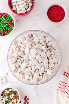 the bowl is full of white and red candy mix next to two bowls with green and red sprinkles