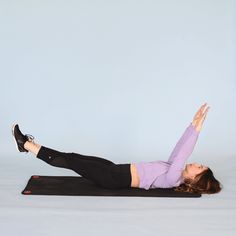 a woman laying on top of a yoga mat with her legs spread out in the air