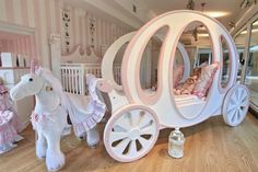 a white horse drawn carriage sitting on top of a hard wood floor next to a baby crib