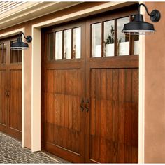 two wooden garage doors on the side of a house next to a light post and lamp