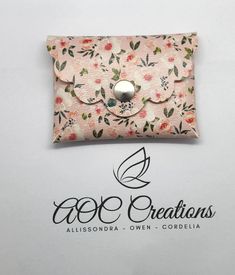 a small pink flowered purse with a button on the front and an inscription above it