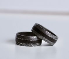 two wedding bands with engraved designs on them sitting next to each other in front of a white background