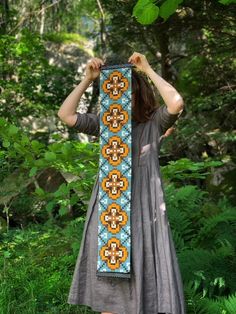 a woman is standing in the woods with her head down and holding up a scarf