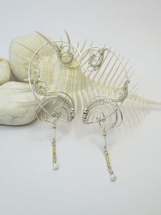 "Average delivery terms USA, France, Ireland - 3-4 weeks Australia, Canada - 4-6 weeks Netherlands, Spain - 2-3 weeks A pair of ear cuffs made of silver plated copper wire white and golden glass beads with delicate danglings. The length of the dangles is 1 1/3\" (3.4 cm). These earrings are covered by metal protecting lacquer. No piercing needed, they are worn behind the ear. Another metal (copper, brass) or beads or length of the dangles are also possible if you prefer to make some changes to t Unique Metal Drop Cartilage Earrings, Unique Adjustable Pierced Ear Climbers, Adjustable Pierced Ear Climbers As Gift, Adjustable Unique Style Ear Climbers, Adjustable Ear Climbers As A Gift, Unique Metal Cartilage Earrings As Gift, Unique Metal Cartilage Earrings For Gift, Unique Gift Cartilage Earrings, Elegant Handmade Body Jewelry As Gift