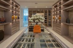 a room filled with lots of glass shelves and drawers next to a vase full of flowers