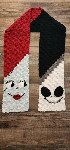 two knitted scarves with faces on them, one is red and the other is black