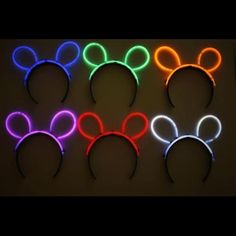 four neon mickey mouse ears are lined up against a black background, with one glowing in the dark