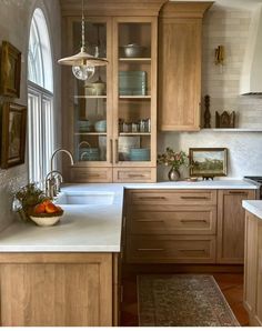 a kitchen filled with lots of wooden cabinets and white counter tops next to a window