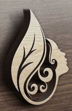 a wooden brooch with a woman's face and swirls on the side