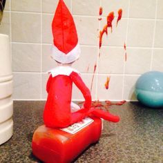 an elf sitting on top of a red object in the middle of a kitchen counter