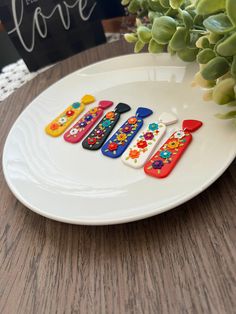 four colorful toothbrushes sitting on top of a white plate next to a potted plant