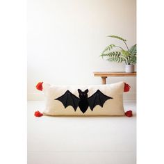 a bat pillow sitting on top of a white floor next to a potted plant