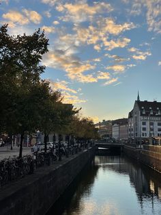 a river running through a city next to tall buildings with bicycles parked on the side