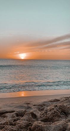 the sun is setting over the ocean on the beach