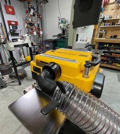 a yellow machine in a shop with lots of tools