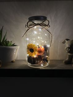 a glass jar filled with fake pumpkins, sunflowers and other decorative items