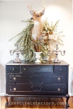 an old dresser is decorated with deer head and greenery for christmas decor on top