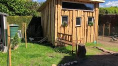 a small wooden shed sitting on top of a lush green field next to a chicken coop