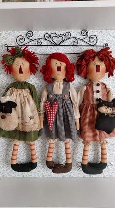 three little dolls are hanging on a wall