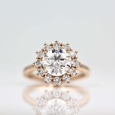 a close up view of a diamond ring on a white surface with reflection in the foreground