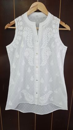 Our Softest Ram Buta Cotton Blouse has front open insert and a beautiful split neckline with asymmetrical hem. Intricately embroidered in chikankari splendour. Front length stands at 27/28 inches and back length stands at 30/31 inches Available in white. Machine wash and light iron for best finish. Available in sizes : XS - bust 34 S - bust 36 M - bust 38 L - bust 40 XL - bust 42 0X - bust 44 1X - BUST 46 Elegant Sleeveless Kurta For Spring, Fitted Sleeveless Kurta For Spring, Sleeveless Self-design Blouse Piece For Summer, Sleeveless Summer Blouse Piece With Self Design, Sleeveless Self Design Blouse Piece For Summer, Elegant Sleeveless Tops With Self Design, Elegant Sleeveless Tops With Intricate Embroidery, Elegant Sleeveless Self Design Tops, Spring Fitted Sleeveless Kurta